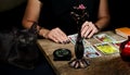 The fortune teller lays out on a wooden table the tarot cards by the light of a candle. Black cat sitting near the table. Royalty Free Stock Photo