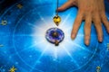 Fortune teller with magic pendulum on blue horoscope like astrology, zodiac. esoteric topic