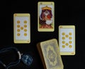 Tarot card reading. Spread out cards on a black background and an old medallion with a stone. Top view