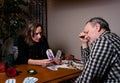 The fortuneteller holds two cards and shows them to the client. A man looks puzzled.