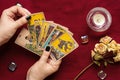 Fortunetellers hand with black manicure lays out tarot cards, crystal, candle, dry roses on red tablecloth Flat lay Top view