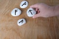 Fortuneteller`s hand explains the meaning of the Scandinavian, Slavic runes on flat stones for fortune-telling for the future, th