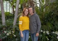 Forty-eight year-old woman posing with her fifty year-old husband in front of beautiful flowers and plants on Mother`s Day.