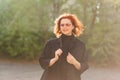 Forty-year-old red-haired smiling woman in sunglasses on a soft blurred background outdoors. Woman in soft contoured sunlight Royalty Free Stock Photo