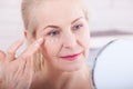 Forty years old woman looking at wrinkles in mirror. Plastic surgery and collagen injections. Makeup. Macro face. Selective focus Royalty Free Stock Photo