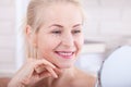 Forty years old woman looking at wrinkles in mirror. Plastic surgery and collagen injections. Makeup. Macro face. Selective focus Royalty Free Stock Photo