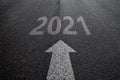 Forward arrow and year 2021 on asphalt as background, new year 2021