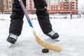 Forward holding black puck with stick, hockey skates on lake ice, teenage male legs, front view Royalty Free Stock Photo