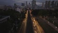 Forwards fly above busy thoroughfare in evening city. Elevated railway line in center of multilane road. Manila