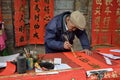 FOSHAN, CHINA - CIRCA JANUARY 2018: An old man writing blessing antithetical couples during the Spring Festival. A translation of Royalty Free Stock Photo