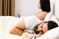 Foto of young couple in the bed. Attractive woman is angy with her sleeping boyfriend. Royalty Free Stock Photo