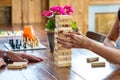 Wooden table full of boardgames being played by a girl and a guy. Cafe setting with a houseroom vibe.