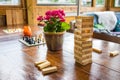 Wooden table full of boardgames being played by a girl and a guy. Cafe setting with a houseroom vibe.