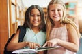 We found what we were looking for. Portrait of two young school girls reading a book together while standing inside of a Royalty Free Stock Photo