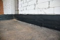 Foundation bitumen waterproofing. Building house construction with waterproofing spray-on tar. Construction techniques for Royalty Free Stock Photo