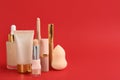 Foundation makeup products on red background, space for text. Decorative cosmetics