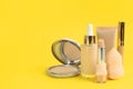 Foundation makeup products on yellow background, space for text. Decorative cosmetics