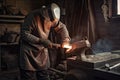 foundry worker, shaping a metal casting with hammer and chisel