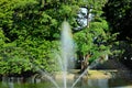 A fountain gushing water over a lake against a background of green trees. Royalty Free Stock Photo