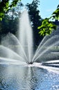 A fountain gushing water over a lake against a background of green trees. Royalty Free Stock Photo