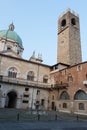 Fountain in the inner yard of medieval palace Palazzo del Broletto with dome of the New Cathedral and Tower of Pegol on background