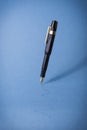 Fountain pen drawing line, hanging in the air on blue isolated background Royalty Free Stock Photo