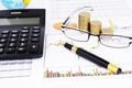 Fountain pen and eyeglasses and coins stack and calculator on stock chart report Royalty Free Stock Photo