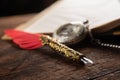 Fountain pen with red feather on a notebook and an old watch, selective focus Royalty Free Stock Photo