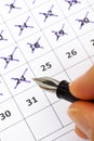 Fountain pen in woman hand marking days on calendar