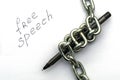 A fountain pen wrapped in an iron chain on sheets of white paper with the inscription free speech the concept of freedom of speech