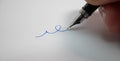 Fountain pen writing on white paper in blue ink. Signing name. Royalty Free Stock Photo