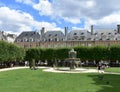 Fountain and people having fun at Place des Vosges. Paris. France. Royalty Free Stock Photo