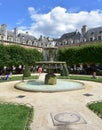 Fountain and people having fun at Place des Vosges. Paris. France. Royalty Free Stock Photo