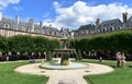 Fountain and people having fun at Place des Vosges. Paris. France. Royalty Free Stock Photo