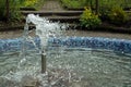 The fountain spouting water from a vertical cylindrical nozzle in a circular pool lined with blue mosaic tiles in par