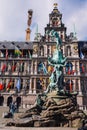 Fountain statue of Brabo throwing the severed hand of Antigoon into the Scheldt river with belfry of the Cathedral of our Lady,