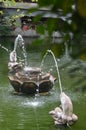 Fountain of stone fish spurting water into a jade-coloured pond