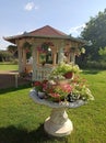 a fountain used for floral decoration and a small concrete, open summer house in the village yard