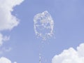 Fountain water splash against blurred sky with clouds, selective focus, shallow DOF Royalty Free Stock Photo