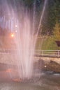 Fountain with water splashes in a night Park with lighting, vertical photo