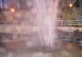 Fountain with water splashes in a night Park with lights, bokeh and blurred background Royalty Free Stock Photo