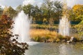 Fountains on pond with island with reeds in autumn park Royalty Free Stock Photo