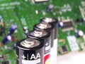 Four AA batteries in a row in front of circuit board Royalty Free Stock Photo