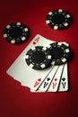 Four aces and black chips on a red table in a casino. Concept of winning with a four of a kind or quads combination in a poker