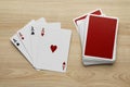 Four aces and deck of playing cards on wooden table, flat lay Royalty Free Stock Photo