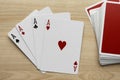 Four aces and deck of playing cards on wooden table, flat lay Royalty Free Stock Photo