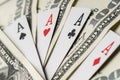 Four aces poker playing cards among U.S. dollars