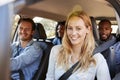 Four adult friends in a car on a road trip smiling to camera Royalty Free Stock Photo