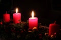 Four advent candles and two burning candles. Black background. Royalty Free Stock Photo