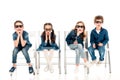 Four amazed kids in 3d glasses sitting on chairs on white.